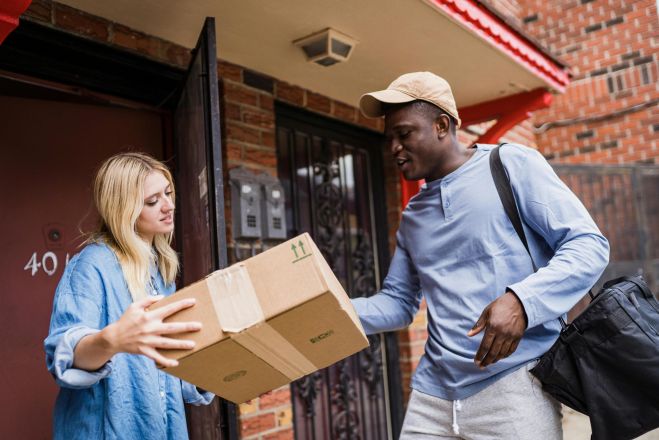 A delivery man handing a package to a woman at her doorstep, emphasizing delivery services.
